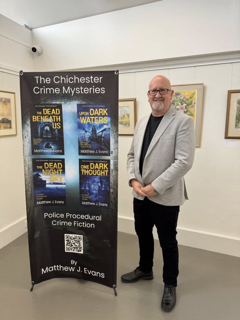 About: Me, standing in front of a banner at the Oxmarket in Chichester